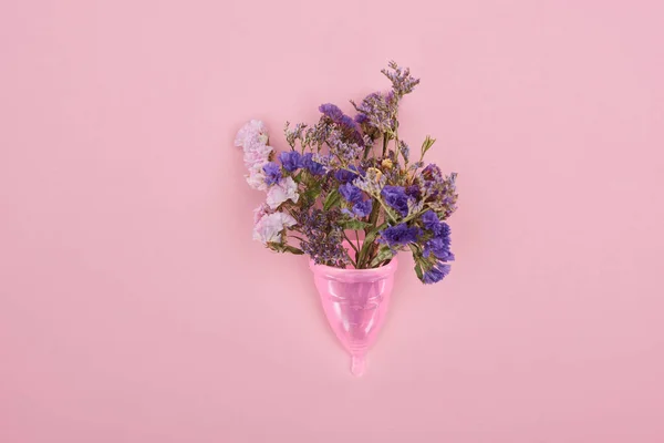 Top view of pink plastic menstrual cup with wildflowers isolated on pink — Stock Photo