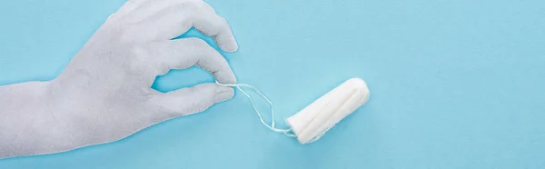 Top view of white paper hand holding cotton tampon on blue background, panoramic shot — Stock Photo