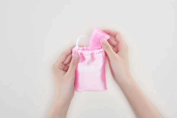 Partial view of woman putting pink plastic menstrual cup in bag isolated on grey — Stock Photo