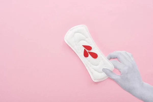 Обрізаний вид руки, що тримає білу гігієнічну серветку з краплями крові на рожевому фоні — стокове фото