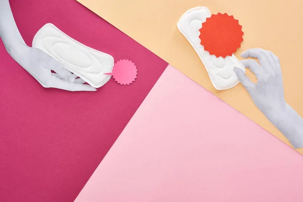 Top view of white hands with sanitary towels and cards on pink, purple and beige background — Stock Photo