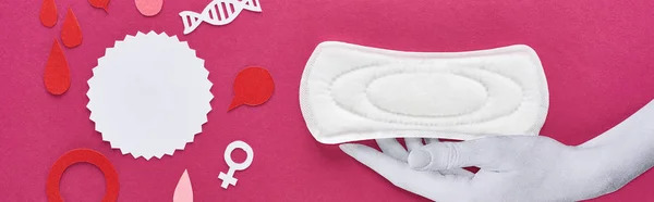 Панорамний знімок паперу вирізав білу руку з білою гігієнічною серветкою біля крапель крові та жіночих знаків на фіолетовому фоні — стокове фото