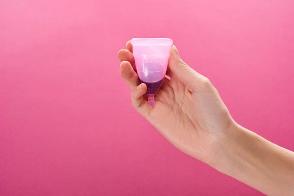 Cropped view of woman holding plastic menstrual cup with blood on purple background — Stock Photo