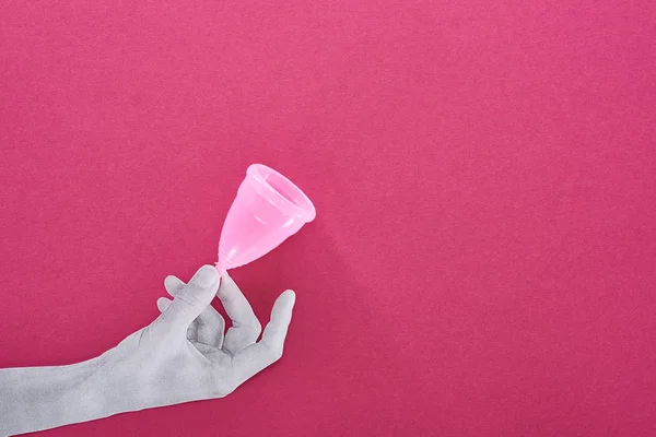 Top view of paper cut white hand with plastic menstrual cup on purple background — Stock Photo