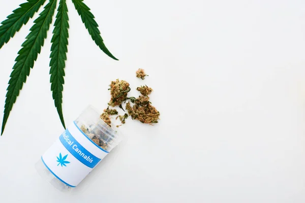 Ansicht von grünem Cannabisblatt und medizinischen Cannabisknospen in der Flasche auf weiß — Stockfoto