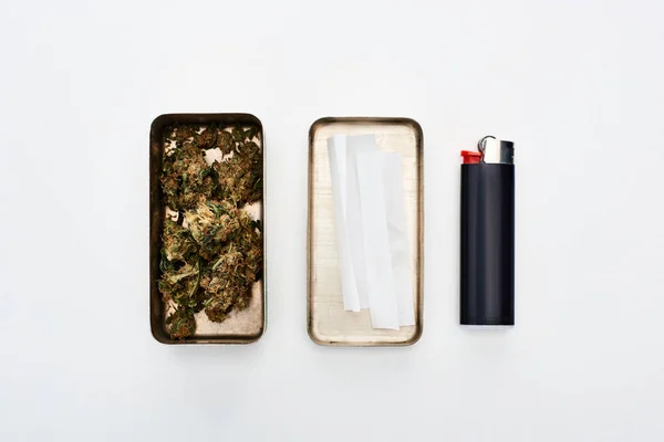 Pose plate avec boîte en métal avec des bourgeons de marijuana et du papier à rouler près de briquet — Photo de stock