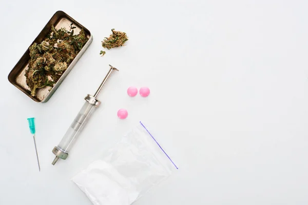 Top view of marijuana buds, heroin, lsd and syringe on white background — Stock Photo