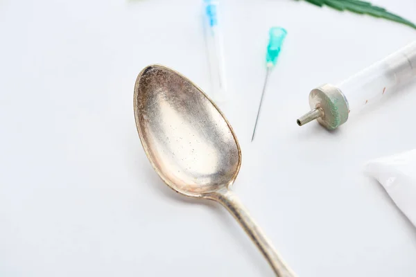 Close up view of silver spoon, syringe and needles on white background — Stock Photo