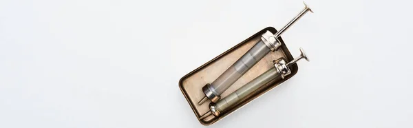 Top view of aged syringes in vintage box on white background with copy space, panoramic shot — Stock Photo