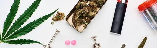 Top view of marijuana buds, cannabis leaf, pills and syringes on white background, panoramic shot — Stock Photo