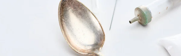 Vista ravvicinata di cucchiaio d'argento, eroina, siringa e ago su sfondo bianco, colpo panoramico — Foto stock