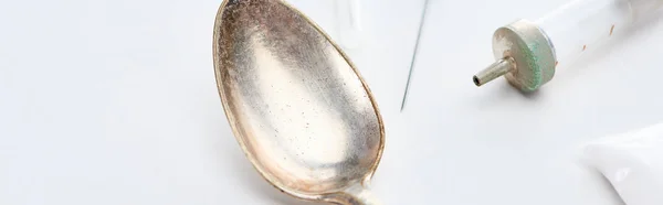 Close up view of silver spoon, heroin, syringe and needle on white background, panoramic shot — Stock Photo