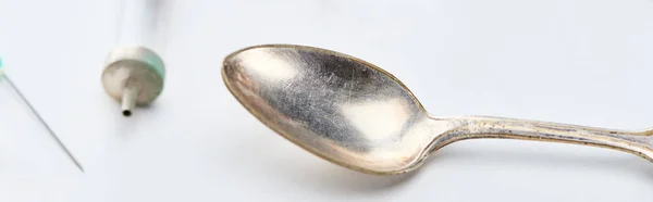 Vista ravvicinata di cucchiaio d'argento, siringa e ago su sfondo bianco, colpo panoramico — Foto stock