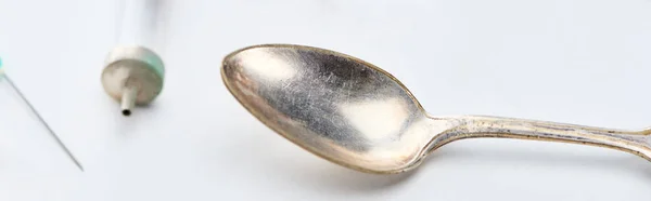 Close up view of silver spoon, syringe and needle on white background, panoramic shot — Stock Photo
