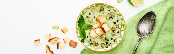 Вид на вкусный сливочно-зеленый овощной суп с тыквенными семечками и гренками подается изолированным на белом, панорамном снимке — стоковое фото