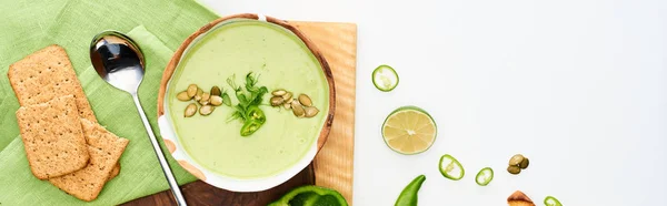 Top view of delicious creamy green vegetable soup served on wooden cutting board isolated on white, panoramic shot — Stock Photo