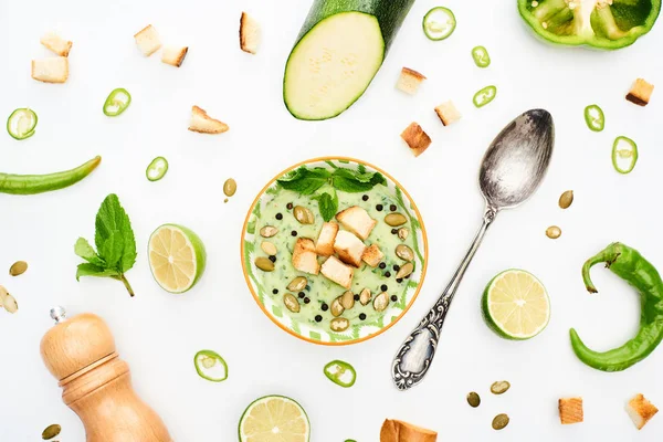 Blick von oben auf köstliche cremige Suppe in der Nähe von grünem Gemüse und Löffel isoliert auf weiß — Stockfoto