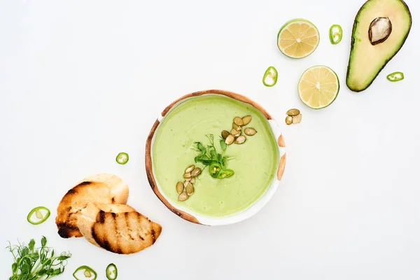 Top view of delicious creamy green vegetable soup with lime and croutons isolated on white — Stock Photo