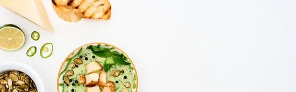 Vista superior de deliciosa sopa de legumes verde cremoso com brotos, croutons grelhados e sementes de abóbora isolado em branco, tiro panorâmico — Fotografia de Stock