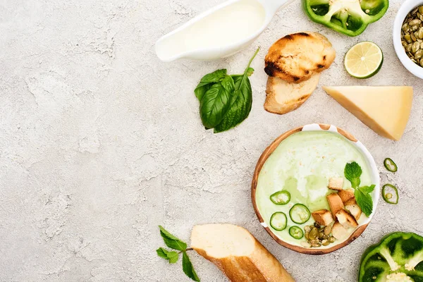 Vista dall'alto di gustosa zuppa verde cremosa con crostini e verde su sfondo grigio strutturato — Foto stock