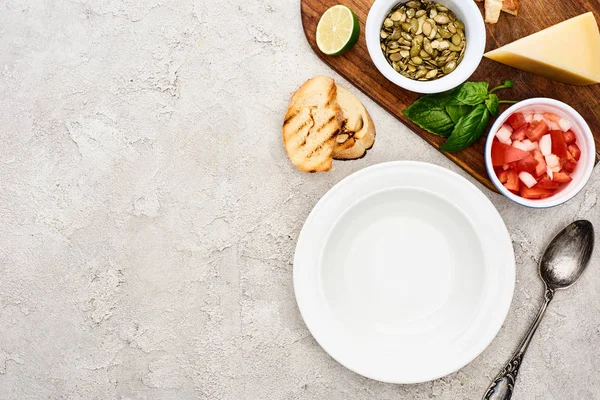 Вид сверху на пустую тарелку возле деревянной доски со свежими ингредиентами — стоковое фото