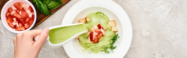 Vista parcial de la mujer añadiendo sopa de puré en plato con ingredientes, plano panorámico - foto de stock