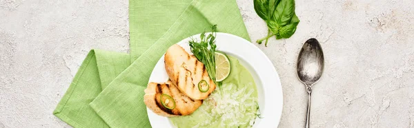 Панорамний знімок смачного вершково-зеленого овочевого супу з грінками, що подаються з серветкою та ложкою — стокове фото
