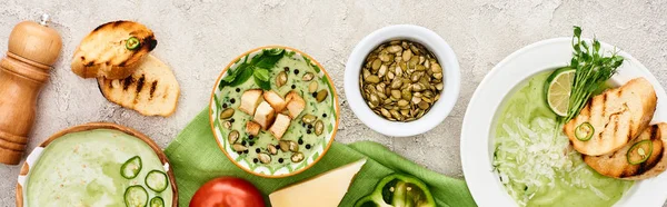 Tiro panorâmico de deliciosa sopa verde cremosa servida com legumes e croutons em guardanapo verde — Fotografia de Stock