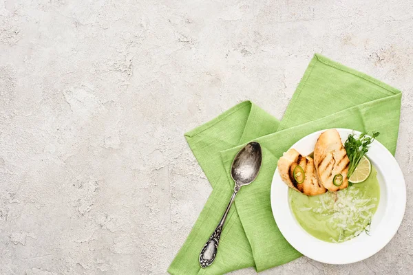 Top view of delicious creamy green vegetable soup with sprouts and croutons served with napkin and spoon — Stock Photo