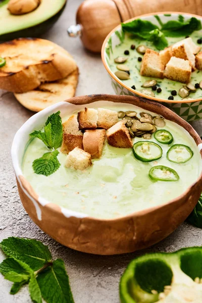 Bols de délicieuse soupe crémeuse de légumes verts avec croûtons croustillants — Photo de stock