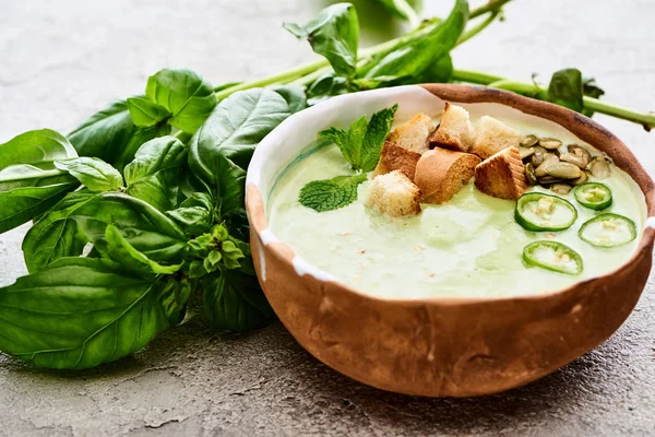 Bowl of delicious green spinach creamy soup with croutons, jalapenos and pumpkin seeds — Stock Photo