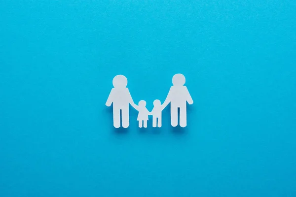 Top view of paper cut family holding hands on blue background — Stock Photo