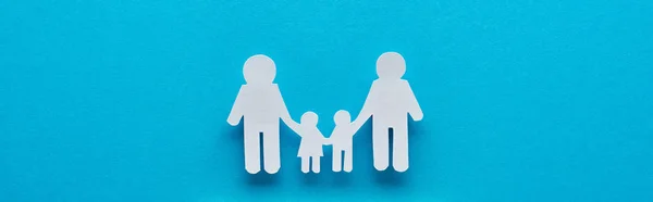 Panoramic shot of paper cut family holding hands on blue background — Stock Photo