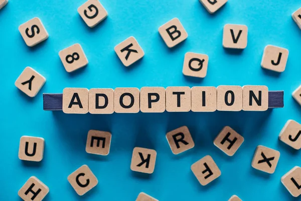 Top view of wooden blocks with adoption lettering on blue background — Stock Photo