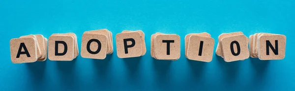 Top view of wooden blocks with adoption lettering on blue background, panoramic shot — Stock Photo