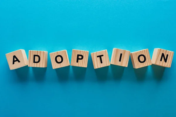 Top view of wooden blocks with adoption word on blue background — Stock Photo