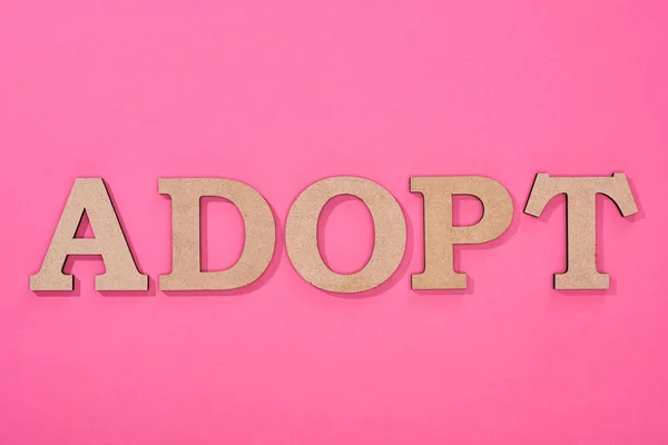 Draufsicht auf Pappe Wort adoptieren auf rosa Hintergrund — Stockfoto