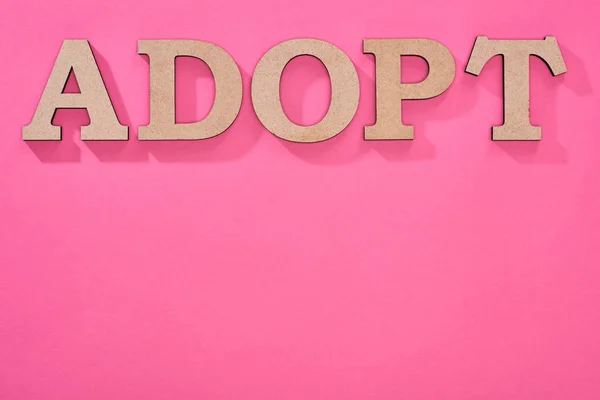 Vista dall'alto della parola di cartone adottare su sfondo rosa con spazio di copia — Foto stock