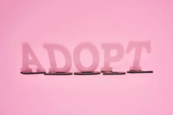 Schatten aus Pappe Wort adoptieren auf rosa Hintergrund — Stockfoto