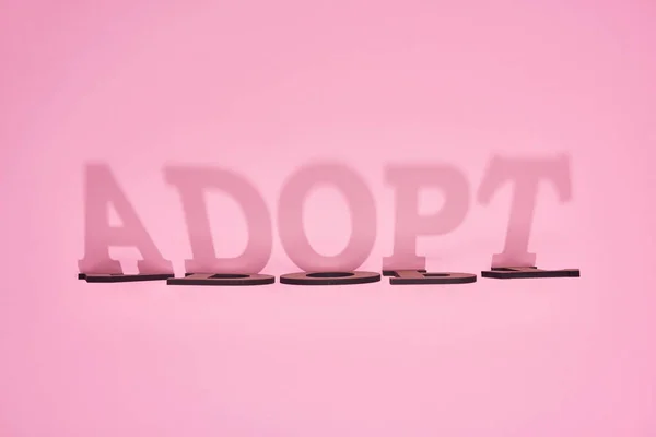 Ombre de mot en carton adopter sur fond rose — Photo de stock