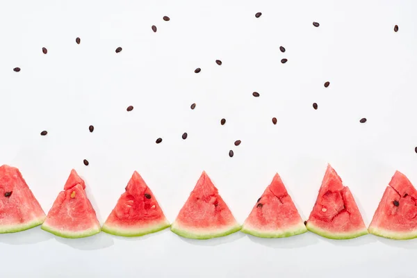 Flat lay com deliciosas fatias de melancia suculentas e sementes espalhadas no fundo branco — Fotografia de Stock