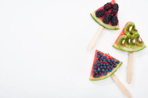 Draufsicht auf köstliche Wassermelonenstäbchen mit saisonalen Beeren und Kiwi auf weißem Hintergrund mit Kopierfläche — Stockfoto