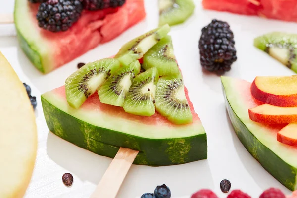 Nahaufnahme von köstlichem Dessert mit Wassermelone am Stiel und Kiwi auf weißem Hintergrund — Stockfoto