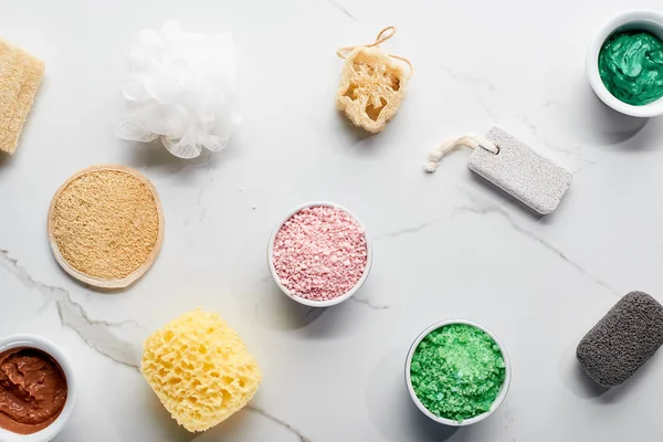 Vue de dessus des éponges de bain de couleur, pierres ponces, sels de bain et masque d'argile sur la surface du marbre — Photo de stock