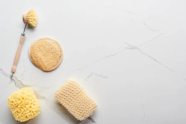 Top view of body brush and bath sponges on marble surface — Stock Photo