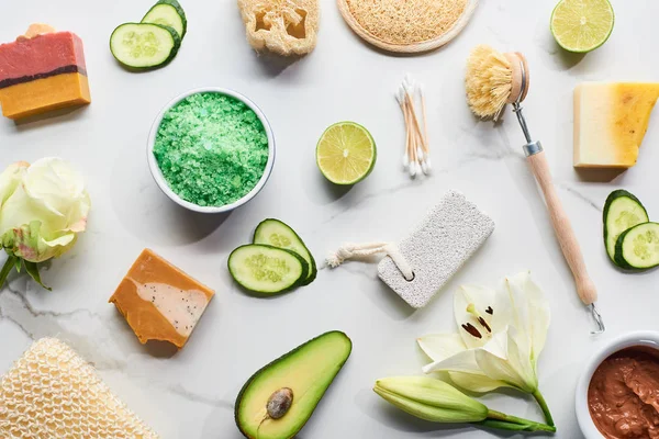 Vue de dessus des produits de beauté naturels et des gadgets et morceaux de savon près des fleurs, légumes et fruits frais sur la surface du marbre — Photo de stock