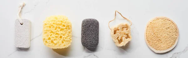 Panoramic shot of bath sponges and pumice stones on marble surface — Stock Photo