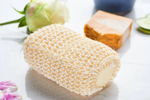 Close up view of bath sponge near natural soap and flower on white surface — Stock Photo