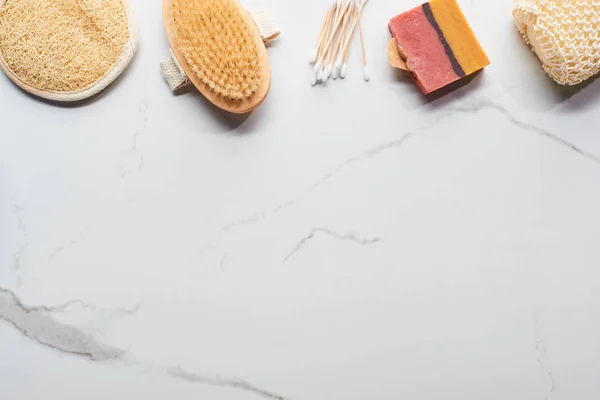 Top view of homemade soap, bath sponges, ear sticks and body brush on marble surface — Stock Photo
