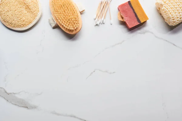 Vista dall'alto di sapone fatto in casa, spugne da bagno, bastoni per le orecchie e spazzola per il corpo sulla superficie di marmo — Foto stock